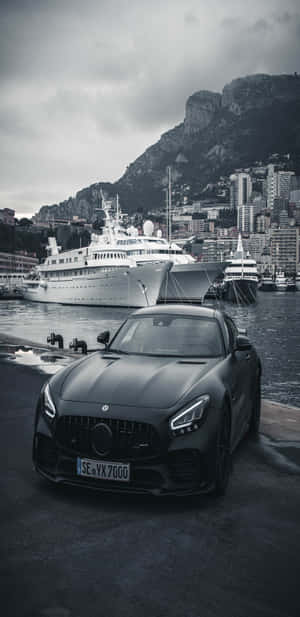 黑色跑車停泊在摩納哥港口，旁邊有豪華遊艇和山脈。 — Mercedes Benz C300 壁紙
