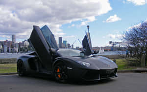 啞黑色藍寶堅尼Aventador，車門打開，在海濱靠近城市天際線，日落時分。 — 豪華車 壁紙