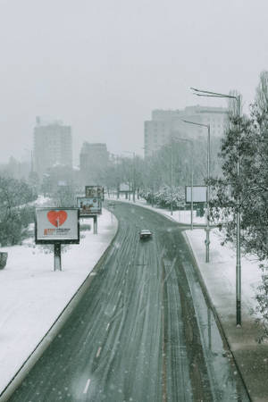 積雪的城市街道，一輛汽車在飄雪和模糊的建築物中行駛。 — 鄉村道路 壁紙