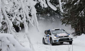 冬季在雪地森林小徑上行駛的拉力賽車。 — 低飽和 壁紙