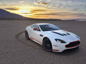 白色Aston Martin跑車停在龜裂的沙漠地面上，夕陽西下。 — 奧斯頓馬丁 壁紙