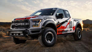 福特 F-150 猛禽賽車卡車停在日落時的沙漠地形上。 — 墜落卡車 壁紙