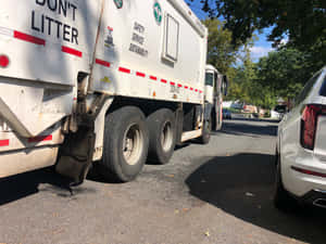 白色垃圾車停在白色SUV旁的陽光明媚街道上，有樹木。 — 老福特卡車 壁紙