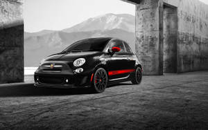 黑色Fiat 500 Abarth帶有紅色條紋，停在雪山附近的混凝土拱門下。 — Mercedes Benz C300 壁紙