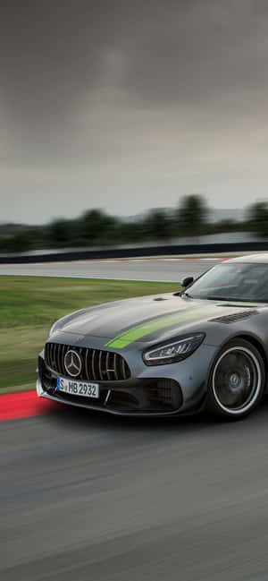 銀色 Mercedes-AMG GT 賽車在潮濕賽道上飛馳，帶有動態模糊效果。 — iPhone 16 Pro Max 壁紙