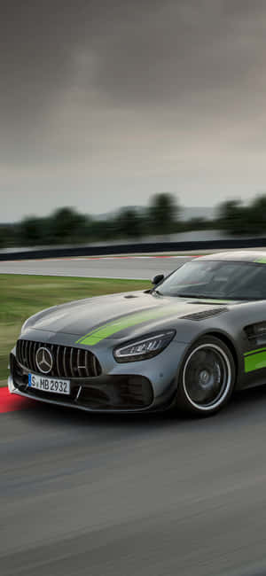 銀色 Mercedes-AMG GT 賽車在潮濕的賽道上快速行駛，帶有綠色條紋。 — iPhone 17e 壁紙