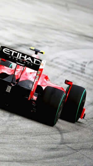 紅黑一級方程式賽車在灰色賽道上飛馳。 — F1 iPhone 壁紙