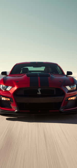 紅色Shelby Mustang在日落時分的道路上疾馳。 — Redmi Note 壁紙