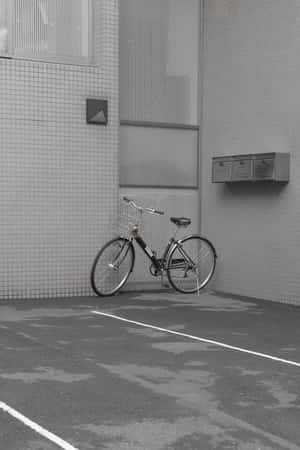 一輛腳踏車靠在瓷磚建築牆上，位於寧靜的城市小巷中。 — 灰色美學動圖 壁紙