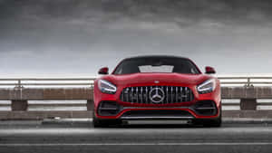 暴風雨天空下，濕滑橋上的紅色 Mercedes-AMG GT 跑車。