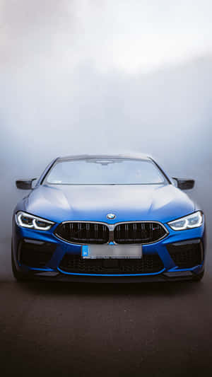 藍色BMW M8 Coupe在迷霧工作室中，頭燈閃爍 — 9:16 壁紙