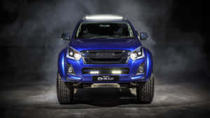 藍色Isuzu D-MAX皮卡車在煙霧繚繞的攝影棚中，車頭燈明亮。 — Pro Display XDR 壁紙
