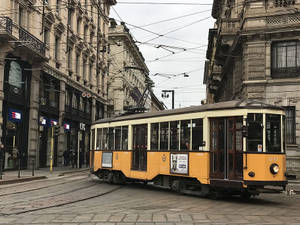 歷史建築之間鵝卵石街道上的復古黃色電車。 — 城市 壁紙