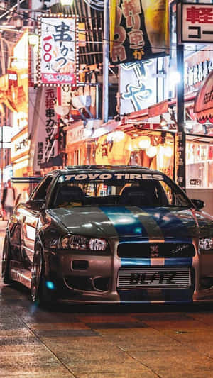 改裝銀色跑車帶藍色條紋，夜晚停在潮濕霓虹燈日本街道上。 — 日產 壁紙