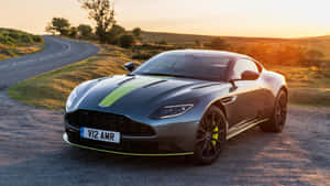 時尚灰色 Aston Martin V12 AMR 搭配綠色點綴，停放在蜿蜒鄉村道路上的日落時分。 — 奧斯頓馬丁 壁紙