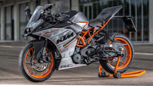 一輛KTM RC 390運動機車停在橙色支架上，位於瀝青路面。 — 巴布風機車 壁紙