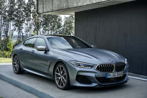 啞光灰色BMW 8系列停在現代混凝土結構下，背景有樹木。 — Mercedes Benz C300 壁紙