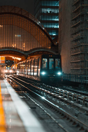 地鐵列車在夜間於城市車站的玻璃天篷下接近。 — 地鐵 壁紙