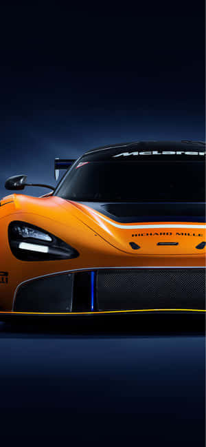 在黑暗的工作室環境中，帶有黑色飾邊和藍色燈光的橙色McLaren賽車。 — iPhone 15 Pro Max 壁紙