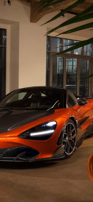 橙色和黑色McLaren跑車在室內靠近窗戶和棕櫚葉展示。 — Galaxy M 壁紙
