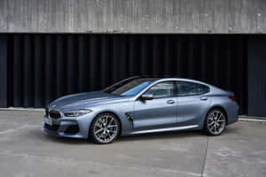 消光藍色BMW 8系列轎跑車停靠在混凝土和金屬牆邊。 — Surface Pro 壁紙