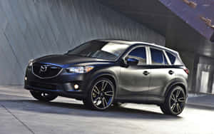 消光黑色馬自達 CX-5 SUV 停放在現代混凝土結構下。 — 馬自達 壁紙