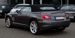 深灰色 Chrysler Crossfire 敞篷車停放在鵝卵石路面上。 — 克萊斯勒 壁紙