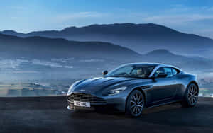 深灰色Aston Martin跑車在懸崖上俯瞰山谷黎明。 — 奧斯頓馬丁 壁紙