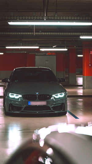 一輛深灰色BMW跑車停在一個光線昏暗、有紅色柱子的地下車庫中。 — 午夜 壁紙