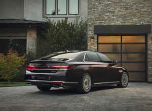 黃昏時分，深紅色Genesis G90豪華轎車停放在現代石屋前。 — 暮光 壁紙
