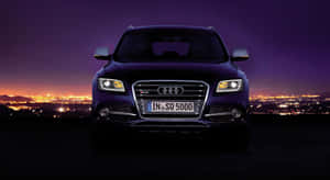 深紫色 Audi SQ5 SUV 在暮色中俯瞰燈火輝煌的城市。 — 奧迪 GIF 壁紙