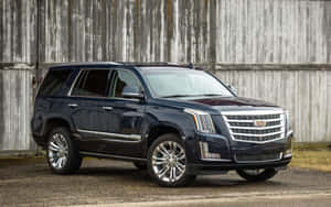 深藍色 Cadillac SUV 停在質樸的木製穀倉前。 — Steam Deck OLED 壁紙