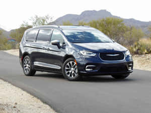 深藍色 Chrysler Pacifica 小型貨車在沙漠公路上，背景有山脈和仙人掌。 — 奧迪 GIF 壁紙