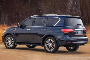 深藍色 Infiniti QX80 SUV 停在森林附近的泥路上。 — Surface Laptop 壁紙