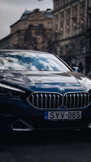 一輛藍色BMW汽車停泊在城市街道上的特寫，背景有歷史建築。 — 9:16 壁紙