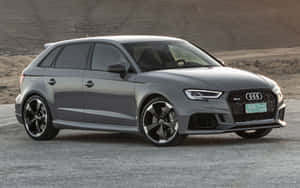 灰色Audi RS3 Sportback停在碎石上，靠近沙漠山丘。 — Steam Deck OLED 壁紙