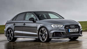 灰色Audi RS3轎車停在濕滑的路面上，背景是陰天和長滿草的山丘。 — 好看汽車 壁紙