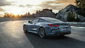 灰色BMW 8系列轎跑車在日落時分行駛在蜿蜒的道路上，背景有岩石丘陵。 — Mercedes Benz C300 壁紙