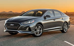 灰色Hyundai Sonata轎車在沙漠公路上金色日落。