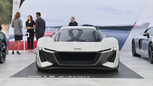白色Audi PB18 e-tron概念車在車展上展出，附近有人群。 — 奧迪 GIF 壁紙