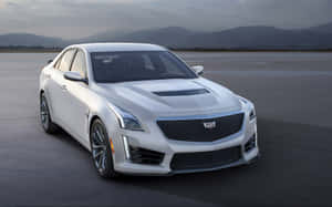 白色Cadillac CTS-V運動轎車在開闊混凝土上，以山巒為背景。 — Steam Deck 壁紙
