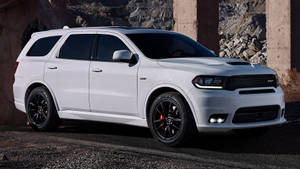 白色Dodge Durango SRT SUV停放在混凝土柱下，靠近岩石地形。 — 汽車 壁紙