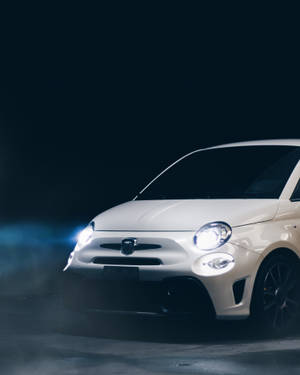 白色Fiat 500汽車在黑暗煙霧繚繞的攝影棚中發出明亮的車頭燈光芒。 — 白色法拉利 壁紙