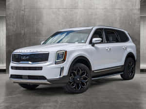 白色Kia Telluride SUV搭配黑色輪圈停放在混凝土工作室中。 — 起亞 壁紙