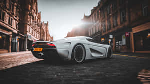 日落時白色Koenigsegg Jesko超跑停在鵝卵石街道上。 — 極限競速 地平線 4 壁紙