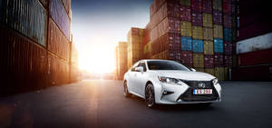 白色Lexus ES 200轎車停放在堆疊的貨運貨櫃之間，夕陽西下。 — 凌志 壁紙
