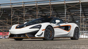 白色McLaren跑車帶有橙色飾邊停在賽道上。 — 麥拉倫 壁紙