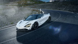 白色McLaren跑車在蜿蜒的山路上，黃昏時分。 — 4K 法拉利 壁紙