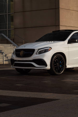 白色Mercedes-AMG GLE63 SUV在日落時停放在現代建築附近的人行道上。 — Mercedes Benz C300 壁紙
