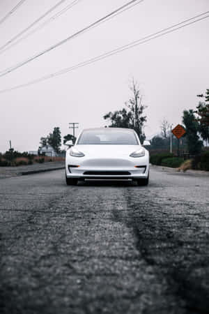 灰色天空下潮濕道路上的白色電動車，帶有電線。 — 小米平板 8 Pro 壁紙